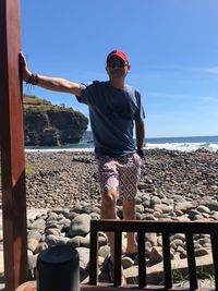 Man standing on pebbles against sea at beach