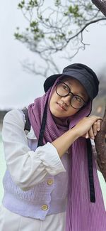 Portrait of young woman wearing hat standing against sky