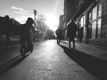 Rear view of people riding bicycle on street in city