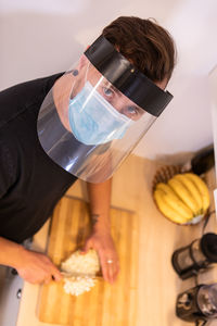 Portrait of man wearing face shield cutting fruit at home