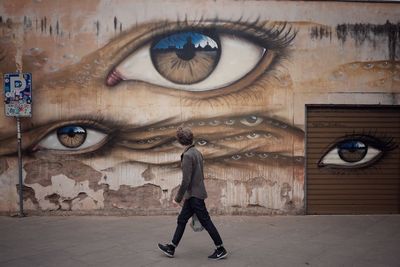 Full length of young woman standing against graffiti wall