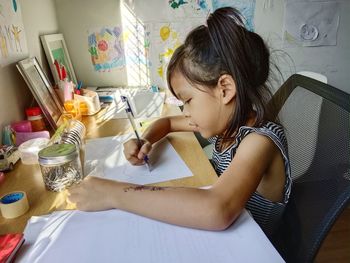 Close-up of girl drawing and coloring at home