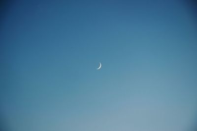 Low angle view of moon against clear blue sky