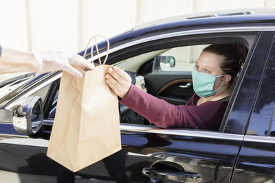 Woman picks up bag from curbside pickup