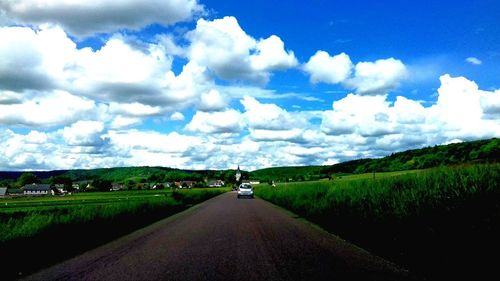 Road amidst green landscape against sky