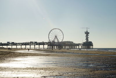 Ferris wheel on beach against clear sky