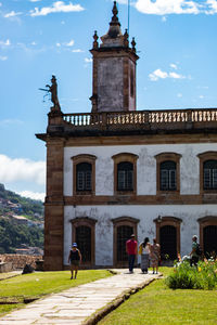 People walking on historic building against sky