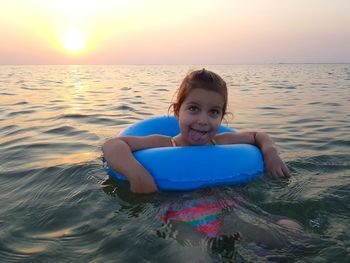 Close-up portrait of girl in sea during sunset