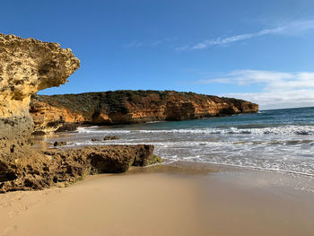 Rock formation on beach against sky