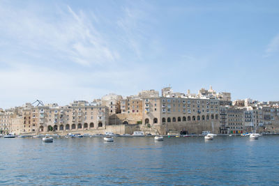 Buildings by river against sky