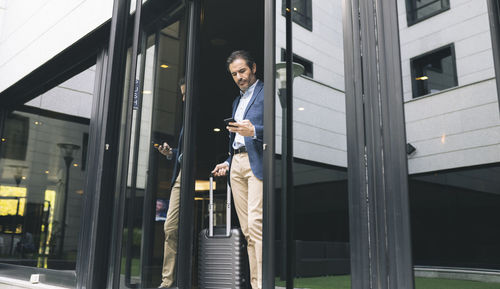 Businessman using mobile phone at hotel doorway