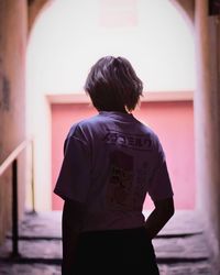 Rear view of woman standing against wall in building