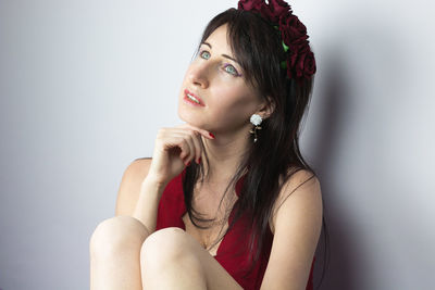 Portrait of beautiful young woman sitting against wall