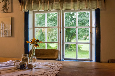 Flower vase on table by window at home