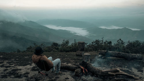 A man is sitting on the peak by the bonfire
