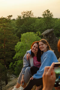 Portrait of smiling friends sitting on mountain