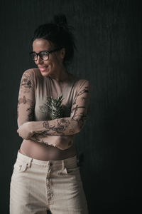 Portrait of smiling young woman standing against black background