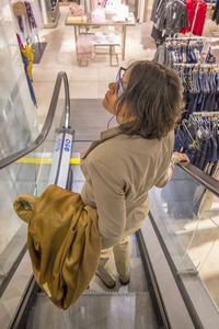 High angle view of woman standing on escalator