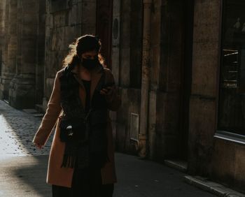 Woman standing by building in city