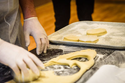 Midsection of man preparing cookies with dough at counter