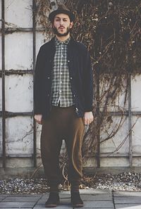 Man winking eyes while standing against ivy wall