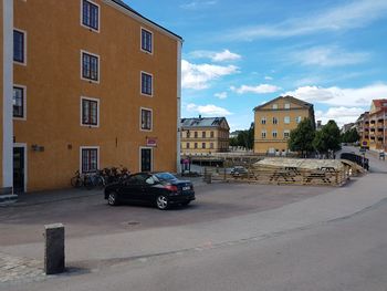 Cars on street by buildings against sky