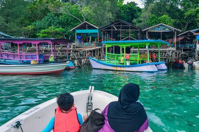 Rear view of people sitting on boat moored in river