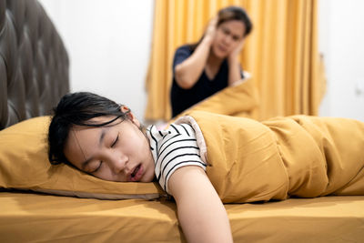 Midsection of woman sleeping on bed at home