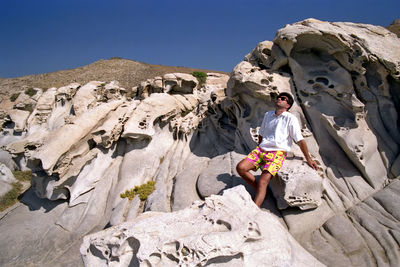 Low angle view of woman on rock against sky