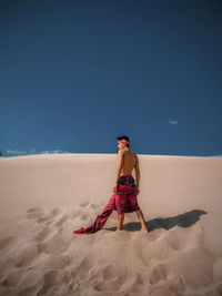 Full length of man on sand at beach against clear sky