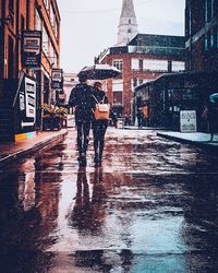 Full length of man with umbrella in puddle during winter