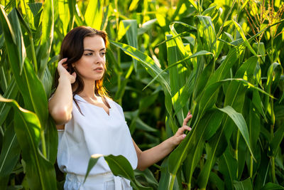 Portrait of young woman standing against plants