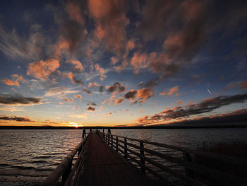 Pier over sea against sky during sunset