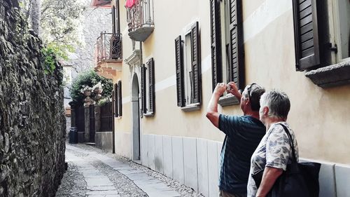 Rear view of man photographing building on street