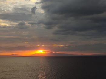 Scenic view of sea against dramatic sky during sunset