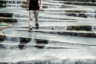 Low section of a boy walking on wet pavement