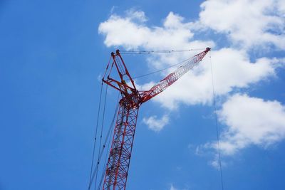 Tall boom crane with blue sky and clouds in background