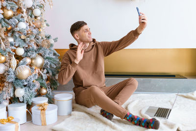 Young caucasian man communicates via video communication using phone in living