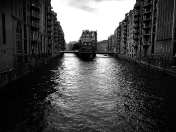 Canal amidst city against sky