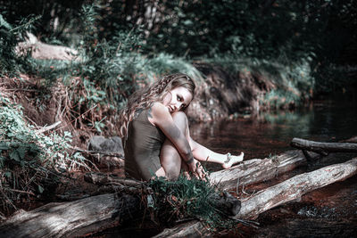 Young woman sitting on wood in forest