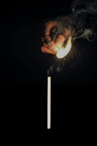 Man holding lit candle in dark room