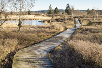 Footpath by lake against sky