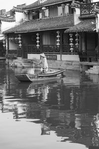 Reflection of woman on river against building