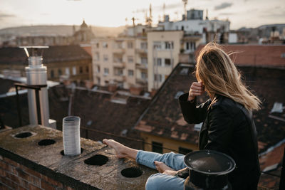 Woman wearing sunglasses while sitting on retaining wall in city