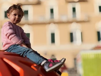 Full length of cute girl sitting on play equipment