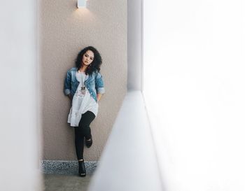 Full length of woman standing against wall