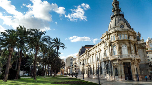 View of historical building and palm trees against sky