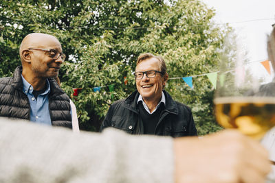 Smiling senior men enjoying garden party at back yard