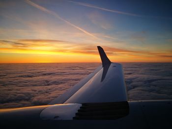 Airplane flying over sea against sky during sunset