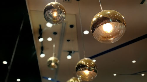 Low angle view of illuminated light bulb hanging on ceiling